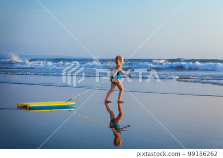 Young surfer girl with bodyboard has fun on sea beach 99186262