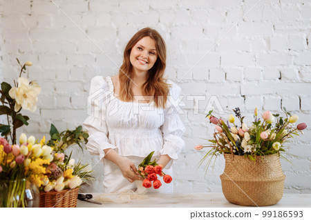 A young florist takes care of flowers in a cozy flower shop 99186593