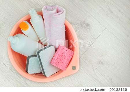 Detergent bottles with washcloths in a pink basin on a wooden background. Top view. Isolate on a white background. Copy space. Detergent bottles with washcloths in a pink basin on a wooden background. Top view. Isolate on a white background. Copy space. 99188156