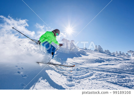 Skier skiing downhill in high mountains against against the fairytale winter forest. Skier skiing downhill in high mountains against against the fairytale winter forest. 99189108