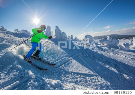 Skier skiing downhill in high mountains against against the fairytale winter forest. Skier skiing downhill in high mountains against against the fairytale winter forest. 99189130