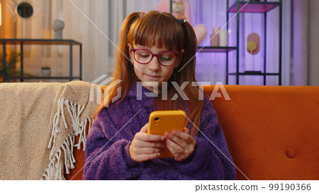 Toddler girl texting share messages on smartphone social media app online watching relax movie, news Toddler girl texting share messages on smartphone social media app online watching relax movie, news 99190366