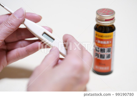 Hand holding a thermometer and Kakkonto oral solution 99190780