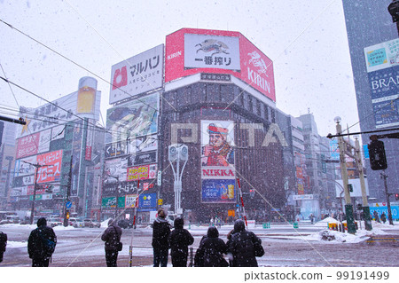 北海道札幌薄野十字路口,繼續下雪的東南方向娛樂區風景,等待紅綠燈的行人 北海道札幌薄野十字路口,繼續下雪的東南方向娛樂區風景,等待紅綠燈的行人 99191499