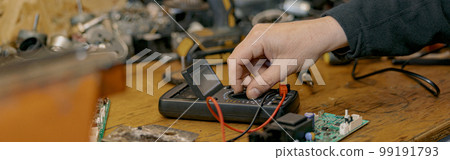 Close up of electrician hands checks the electrical voltage on the circuit board with a device Close up of electrician hands checks the electrical voltage on the circuit board with a device 99191793