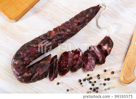 French tasty slicing dry-cured sausage with liver at wooden desk French tasty slicing dry-cured sausage with liver at wooden desk 99193575