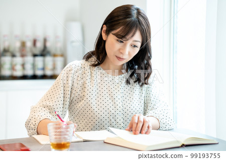 Middle-aged woman studying at the dining table 99193755
