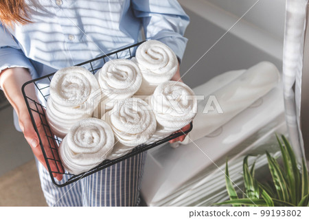 Woman's hands neatly putting or displaying a clean rolled up white towels made from organic cotton. Woman's hands neatly putting or displaying a clean rolled up white towels made from organic cotton. 99193802
