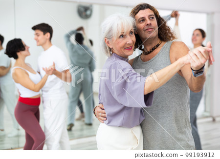Positive adult man and smiling aged woman dancing in pair Positive adult man and smiling aged woman dancing in pair 99193912