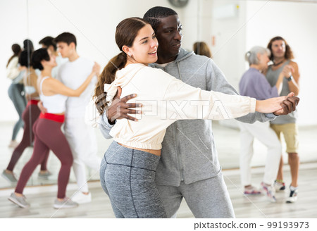 African man and caucasian lady rehearsing latin paired dance moves 99193973