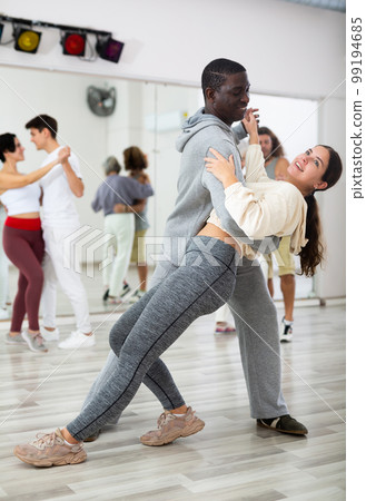 Smiling man supporting gir while dancing slow foxtrot in pair 99194685