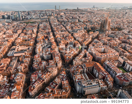 Aerial view of Barcelona City Skyline and Sagrada Familia Cathedral at sunset. Eixample residential famous urban grid. Cityscape with typical urban octagon blocks Aerial view of Barcelona City Skyline and Sagrada Familia Cathedral at sunset. Eixample residential famous urban grid. Cityscape with typical urban octagon blocks 99194773