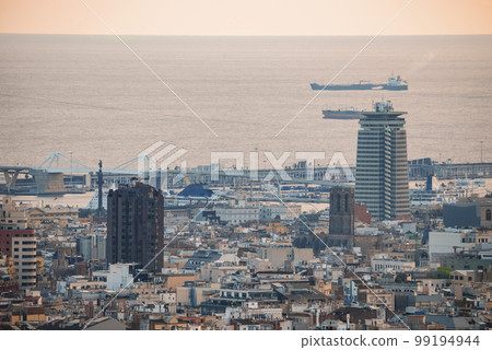 Drone shot of ships sailing on beautiful seascape and buildings at the Moll de Gregal del Port Olympic in Barcelona, Catalunya, Spain during sunset 99194944
