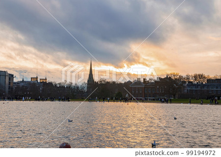 Scenic view of beautiful lake and garden with St Mary Abbots church and Kensington Palace in the background. Cloudy day during sunset in London Scenic view of beautiful lake and garden with St Mary Abbots church and Kensington Palace in the background. Cloudy day during sunset in London 99194972