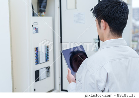 Male worker inspecting the switchboard Male worker inspecting the switchboard 99195135