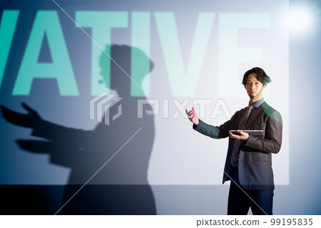 A young business person giving a speech with a slide in the background 99195835