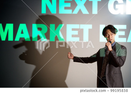 A young business person giving a speech with a microphone on the background of a slide A young business person giving a speech with a microphone on the background of a slide 99195838