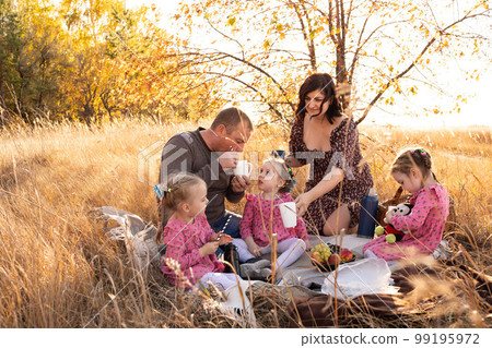 Young family with triplet girls on picnic, eco-friendly paper tubes, biodegradable materials. Young family with triplet girls on picnic, eco-friendly paper tubes, biodegradable materials. 99195972