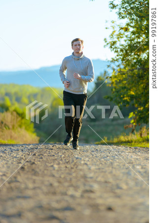 Man jogging in rural nature at beautiful summer day. Sport fitness model caucasian ethnicity training outdoor. Man jogging in rural nature at beautiful summer day. Sport fitness model caucasian ethnicity training outdoor. 99197861