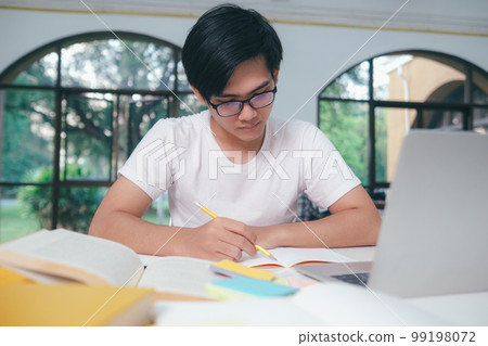Young Asian male student is preparing to reading a books for exams at university. 99198072