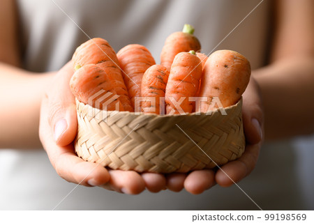 Organic carrot holding by woman hand, Vegetables from local farmers market in spring season, Sustainability concept Organic carrot holding by woman hand, Vegetables from local farmers market in spring season, Sustainability concept 99198569