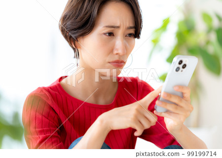 Middle woman operating a smartphone in the room 99199714