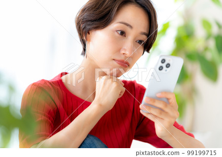 Middle woman operating a smartphone in the room 99199715