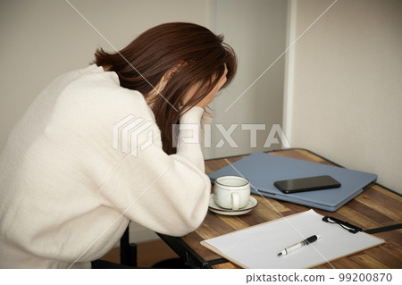 一個女人在她的辦公桌前抱著頭 麻煩 99200870