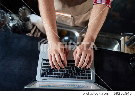 cropped image of a male bartender using a laptop. cropped image of a male bartender using a laptop. 99201846