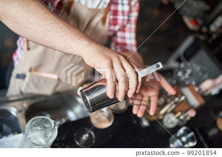 professional male bartender pours a cocktail from a shaker. professional male bartender pours a cocktail from a shaker. 99201854