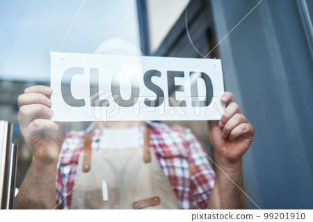 cropped image of a male bartender standing with a closed sign. cropped image of a male bartender standing with a closed sign. 99201910