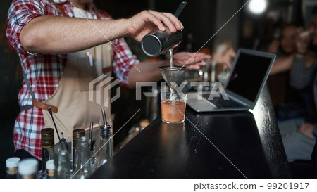 male bartender pouring a cocktail from a shaker. best service. male bartender pouring a cocktail from a shaker. best service. 99201917