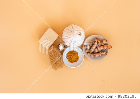 Top view of herbal compress ball with Thai herbal, turmeric, essential oil and bar soap on orange pastel background. Spa background concept. Top view of herbal compress ball with Thai herbal, turmeric, essential oil and bar soap on orange pastel background. Spa background concept. 99202193