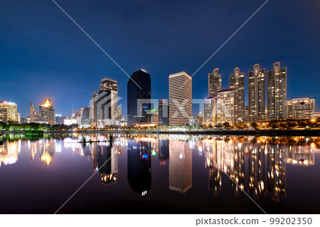 Night, modern highrises reflecting in lake by park. Bangkok, Thailand. Beautiful landscape, residential area. 99202350