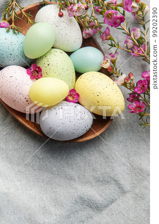 Easter decor. Colored Easter eggs on a wooden plate on the table. Easter decor. Colored Easter eggs on a wooden plate on the table. 99202390