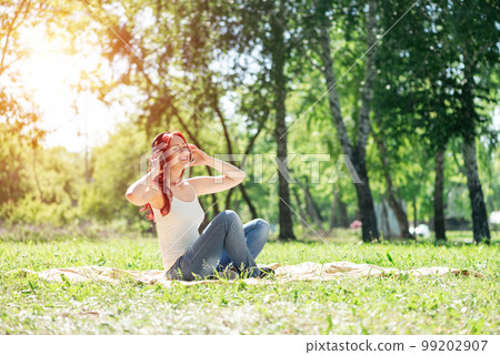 Young woman happens to have music in a summer park 99202907