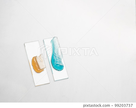 Samples of a multicolored cosmetic product on a laboratory glass on white background Samples of a multicolored cosmetic product on a laboratory glass on white background 99203737