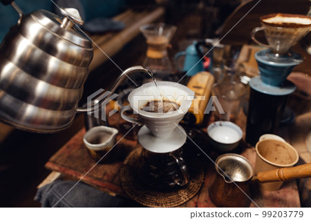 Man pouring hot water on ground coffee with paper filter to making a drip coffee 99203779