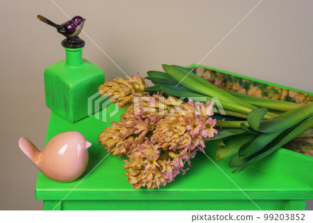 Bouquet of yellow-orange hyacinths on a green stand with spring decorations 99203852