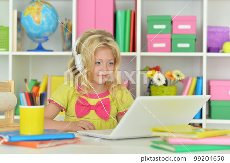 girl in headphones ding with laptop sitting at desk girl in headphones ding with laptop sitting at desk 99204650