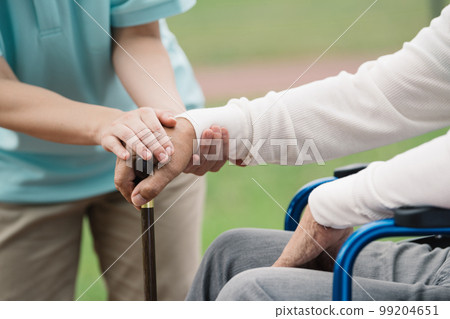 A caregiver helping a man on a wheelchair A caregiver helping a man on a wheelchair 99204651