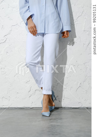 Female legs in white jeans blue shirt and high heel shoes Female legs in white jeans blue shirt and high heel shoes 99205131