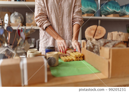 Close up of woman is packing handmade candles for selling in own home decor studio Close up of woman is packing handmade candles for selling in own home decor studio 99205231