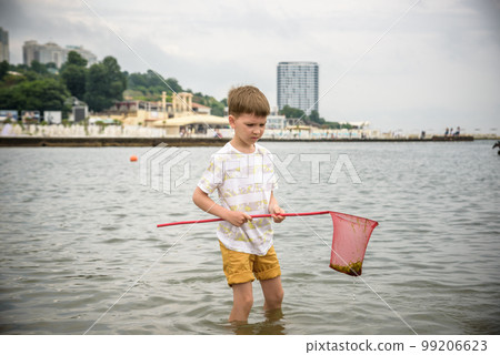 One little boy alone exploring the beach at low tide walking towards the sea coast. happy childhood concept 99206623