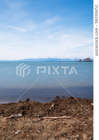 A plastic bottle washed up on the lakeshore with a spectacular view A plastic bottle washed up on the lakeshore with a spectacular view 99208452