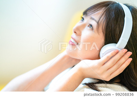 Middle-aged woman listening to music with headphones Middle-aged woman listening to music with headphones 99208836