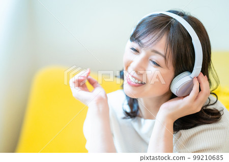 Middle-aged woman listening to music with headphones Middle-aged woman listening to music with headphones 99210685
