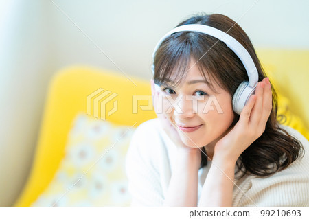 Middle-aged woman listening to music with headphones Middle-aged woman listening to music with headphones 99210693