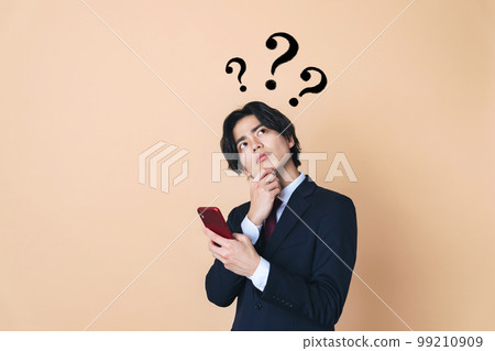 Young businessman thinking with a smartphone 99210909