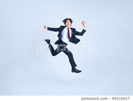 拿著咖啡杯跳躍的年輕商人 99210927